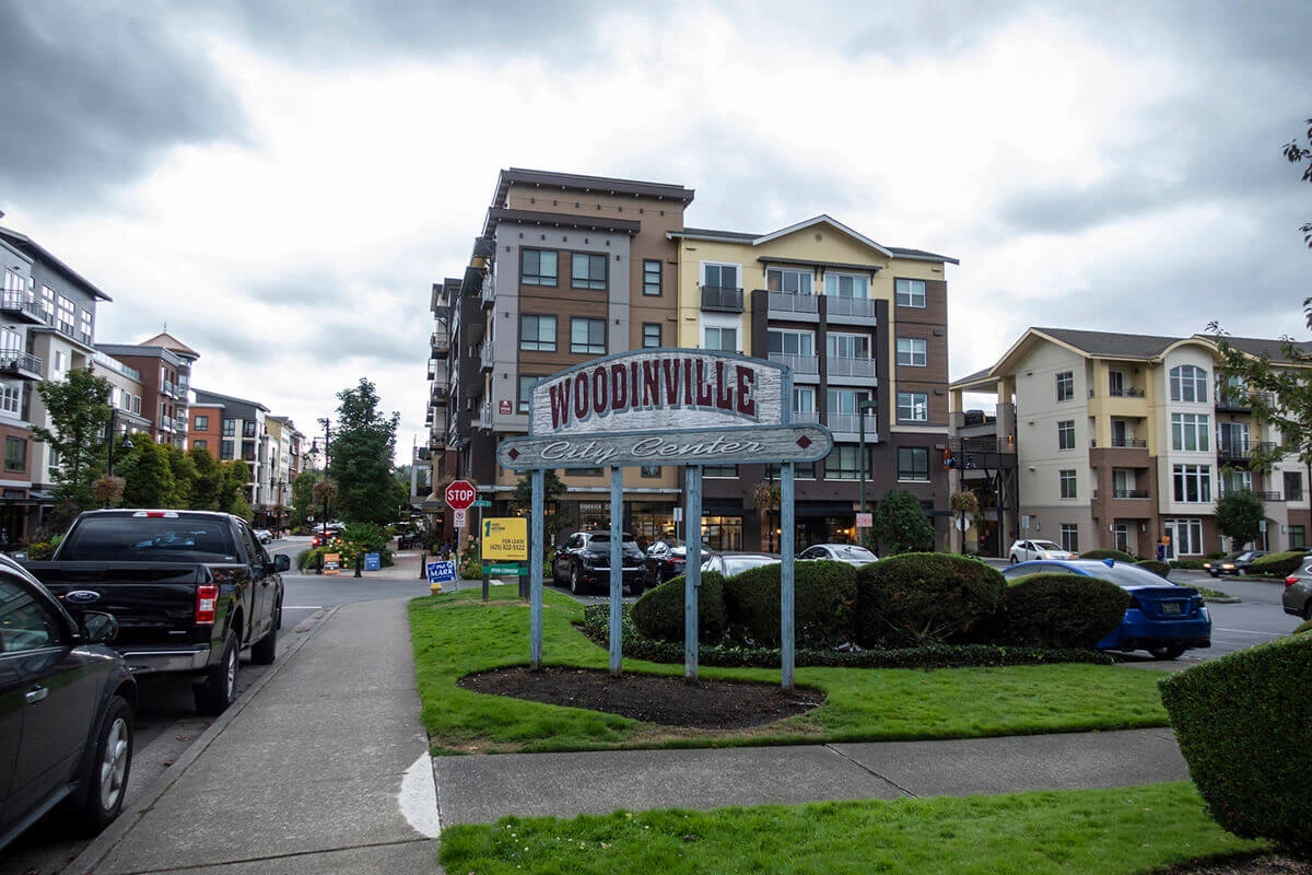 Street view of the Woodinville city center sign outside of a major shopping area on a cloudy, overcast day