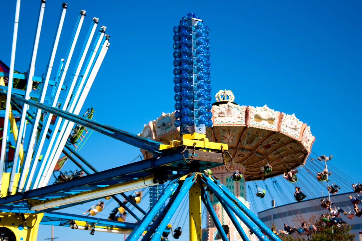 People enjoying the rides at the Washington State Fair in Puyallup, WA at sunset. The Fair is known by locals as the Puyallup fair and has been running since 1900.